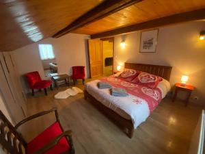 a bedroom with a bed and two red chairs at Le Fenil-Logis Sauna Bain Nordique Salle cinéma in Ban-sur-Meurthe-Clefcy