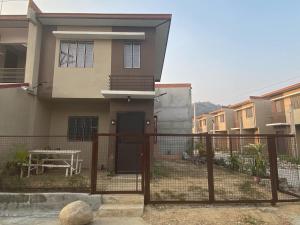 a house with a fence and a table in front of it at Cozy Rustic Corner House Subic in Subic
