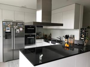 uma cozinha com uma bancada preta e uma geladeira em Modern and stylish Home in Muttenz em Muttenz