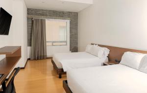 a hotel room with two beds and a television at Hotel Viaggio Nueve Tres in Bogotá +45 photos