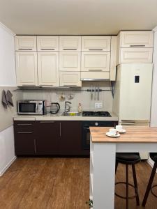 a kitchen with white cabinets and a wooden counter top at Светлая 2 спальная квартира в историческом центре Астаны in Astana +2 photos