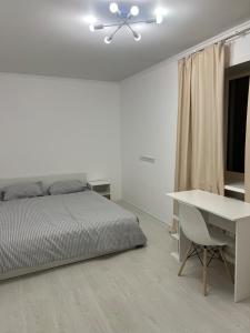 a white bedroom with a bed and a desk at Светлая 2 спальная квартира в историческом центре Астаны in Astana