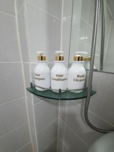 a shelf in a bathroom with four bottles on it at Residence Stay Avenu in Ulsan