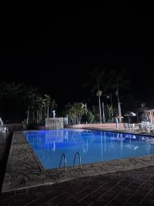 a large blue swimming pool at night at Flat Cavalinho Branco 119 in Águas de Lindoia