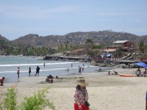 Eine Frau, die am Strand steht, mit einer Menschenmenge. in der Unterkunft Beautiful Casita at La Madera Beach, Zihuantanejo in Zihuatanejo