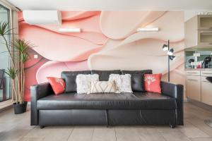 a black leather couch in a living room with a pink wall at Village Naturiste R4N - Sixty9 Port Ambonne in Cap d'Agde