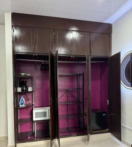 a closet with purple walls and a microwave at Little Bern #1, your little oasis with pool access in San Mateo