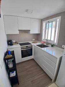 a kitchen with white cabinets and a sink and a window at Tramontana Villa in Cala en Porter