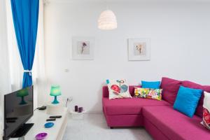 a living room with a pink couch and a tv at Apartamento Hércules in Costa Del Silencio