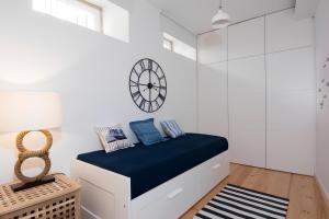 een slaapkamer met een bed met een klok aan de muur bij Casa do Castelo 1- Work or Relax in the Historic heart of Lisbon! in Lissabon