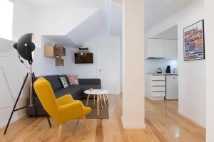 een woonkamer met een gele stoel en een bank bij Casa do Castelo 1- Work or Relax in the Historic heart of Lisbon! in Lissabon