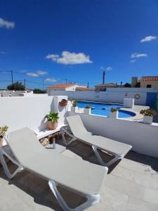 two white chairs sitting on a patio with a pool at Tramontana Villa in Cala en Porter