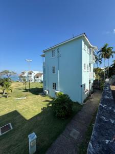 Orange BayNegril beachfront oceanview studios 164 & 145的一座白色的建筑,旁边是棕榈树