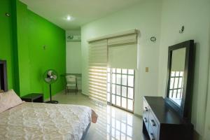 a bedroom with green walls and a bed and a mirror at Large Villa private pool, 1 block from the beach in Chicxulub +39 photos