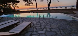 a swimming pool with two benches and a sunset at VILLA KASABLANCA in Skala Rachoniou