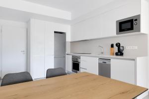 a white kitchen with a wooden table and chairs at Valentino Golf II Luxury in Orihuela