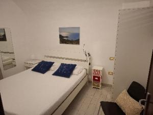 a white bedroom with a bed with blue pillows at Casa San Giorgio in Giglio Porto