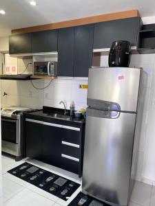 a stainless steel refrigerator in a kitchen with black cabinets at Apartamento Temporada Praias Litoral sul João Pessoa in João Pessoa