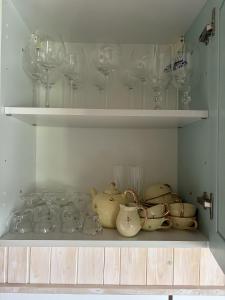 a shelf filled with glasses and tea pots and cups at Golden spur cottage in Pulfero +25 photos