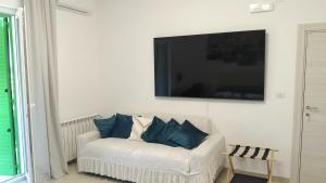 een woonkamer met een witte bank met een televisie aan de muur bij Vello Blu in Giovinazzo
