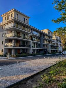 a large apartment building with a group of animals walking in front at Forest Apartment in Pobierowo