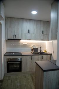 a kitchen with wooden cabinets and a stove top oven at Apartman Stefan in Novi Sad