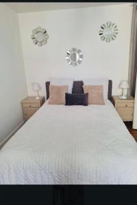 a bedroom with a white bed with two mirrors on the wall at Appartement 2-4 pers in Souillac