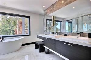ein Badezimmer mit zwei Waschbecken, einer Badewanne und einem großen Fenster in der Unterkunft Villa St-Laurent et spa - Au coeur de Charlevoix ! in La Malbaie + 97 Fotos