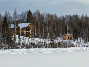 a log cabin in the snow next to a lake at New modern log villa in Äkäsjoensuu