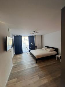 a bedroom with a bed with blue curtains and wooden floors at Le Local DesTiercelins in Nancy