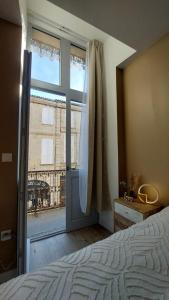 a bedroom with a large glass door and a window at Le Réverbère, appartement de vacances in Lectoure