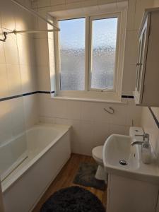 a bathroom with a tub and a toilet and a sink at Square, easy access in Parkstone +6 photos