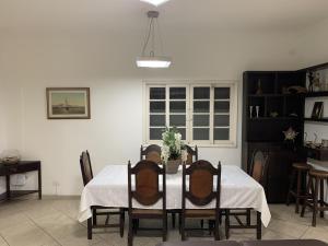 a dining room table with a white tablecloth and chairs at ESPAÇO guaru in Guarujá
