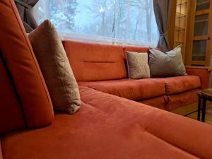 an orange couch with pillows sitting in front of a window at Tin in Marcilly-sur-Eure
