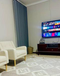 a living room with two chairs and a flat screen tv at LE The Lustrous Home in Gaborone
