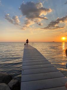 a person standing on a dock in the water at sunset at Ölandspärlan 2 in Färjestaden