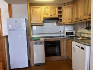 a kitchen with a white refrigerator and wooden cabinets at BPirineos-Senarta in Benasque