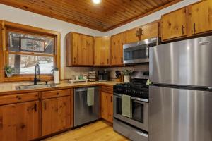 a kitchen with wooden cabinets and a stainless steel refrigerator at Lucky Log Cabin Hottub fireplace 12min to Mt Snow in Wardsboro