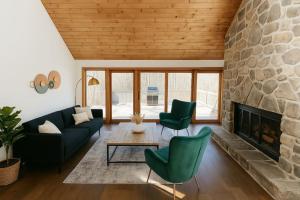 a living room with a stone fireplace and green chairs at Drift Haus 4.5BR Mountain Lodge in Windham