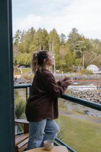 a woman standing on a balcony looking out the window at Tofino Eco Waterfront Condo in Tofino