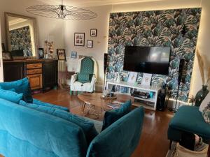 a living room with blue couches and a flat screen tv at Parenthèse de rêve - Piscine & confort au Mans in Coulaines