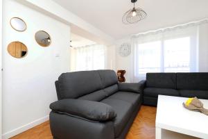 a living room with a black couch and a table at Le Manalac votre Appartement 4-6P au centre ville in Gérardmer