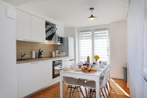 a white kitchen with a white table and chairs at Le Manalac votre Appartement 4-6P au centre ville in Gérardmer