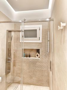 a bathroom with a shower with a tv on the wall at DelMar Suites Syros in Finikas +55 photos