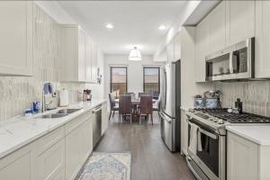 a kitchen with white cabinets and a dining room at Brick Beauty Downtown, 3BR, Fenced Yard, Garage! in Cedar Falls