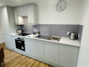 a kitchen with white cabinets and a clock on the wall at Princes Street Executive Apartment 2 in Thurso