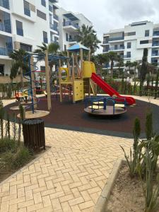 einen Spielplatz vor einem Gebäude mit Rutsche in der Unterkunft Modern 2-room with pool, close to beach, private parking in Martil + 24 Fotos