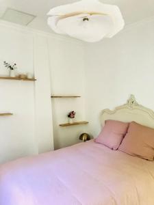 a bedroom with a pink bed and a chandelier at Villa Mini Romy with outdoor area in Parmain