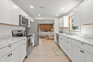 une cuisine avec des armoires blanches et un salon dans l'établissement Riverside Retreat - Renovated Home on 15 Acres!, à Janesville