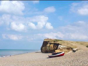 a boat sitting on a beach next to a cliff at The Oaks Tent Pitches with no accommodation supplied and you must bring your own tent in Colkirk